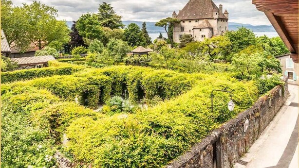 A castle surrounded by lush greenery and a stone wall.