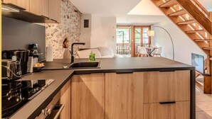 A modern kitchen with a central island, wooden cabinets, and a stone backsplash.
