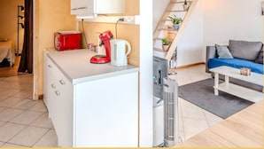 A compact living space with a kitchenette, a sofa, and a staircase. - Chez Amel & Val I T2 I Annemasse (Annemasse)