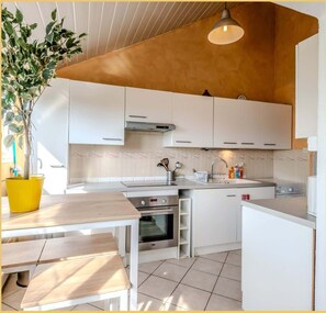 Una cocina moderna con armarios blancos, encimera de madera y horno empotrado.