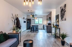 A modern kitchen with a central island, bar stools, and a dining area with a sofa.