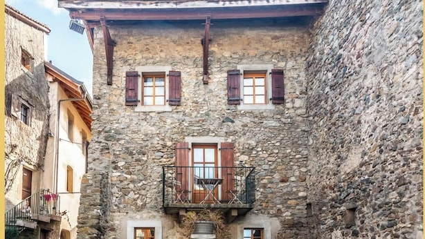 A stone building with a central courtyard, a fountain, and a balcony with wooden shutters.
