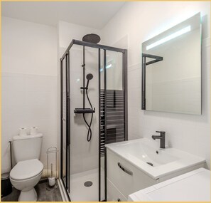Une salle de bain moderne avec une douche à parois de verre, un lavabo blanc et un grand miroir.