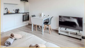 A modern living space with a kitchen, dining area, and a TV.