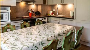 Una cocina compacta con armarios blancos, un microondas y una mesa de comedor con sillas.