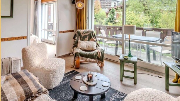 Amplia sala de estar con un gran ventanal, un sillón cómodo, una mesa redonda y vistas al exterior.