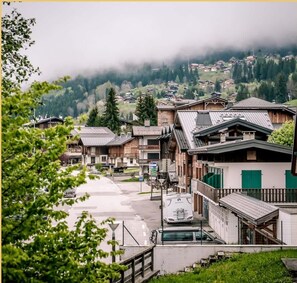 Un village traditionnel avec des bâtiments en bois, une rue pavée et une vue sur une région montagneuse.