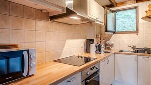 Una cocina compacta con microondas integrado, estufa y pileta.