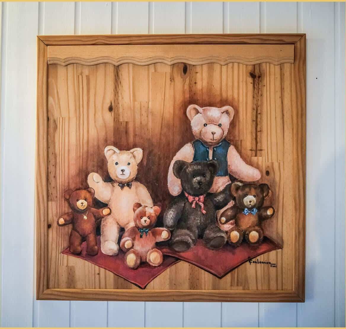 Une œuvre d’art encadrée représentant des ours en peluche sur un fond en bois.