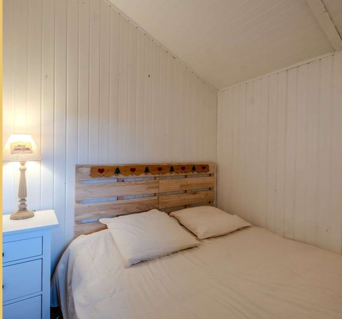 Une chambre à coucher avec une tête de lit en bois, une table de chevet avec une lampe et un lit avec deux oreillers.