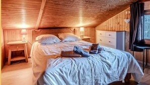 Un dormitorio acogedor tipo cabaña de madera, con una cama grande, mesitas de noche y un aparador.