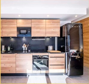 Een moderne keuken met houten kastjes, een zwarte koelkast, een magnetron en een vaatwasser.