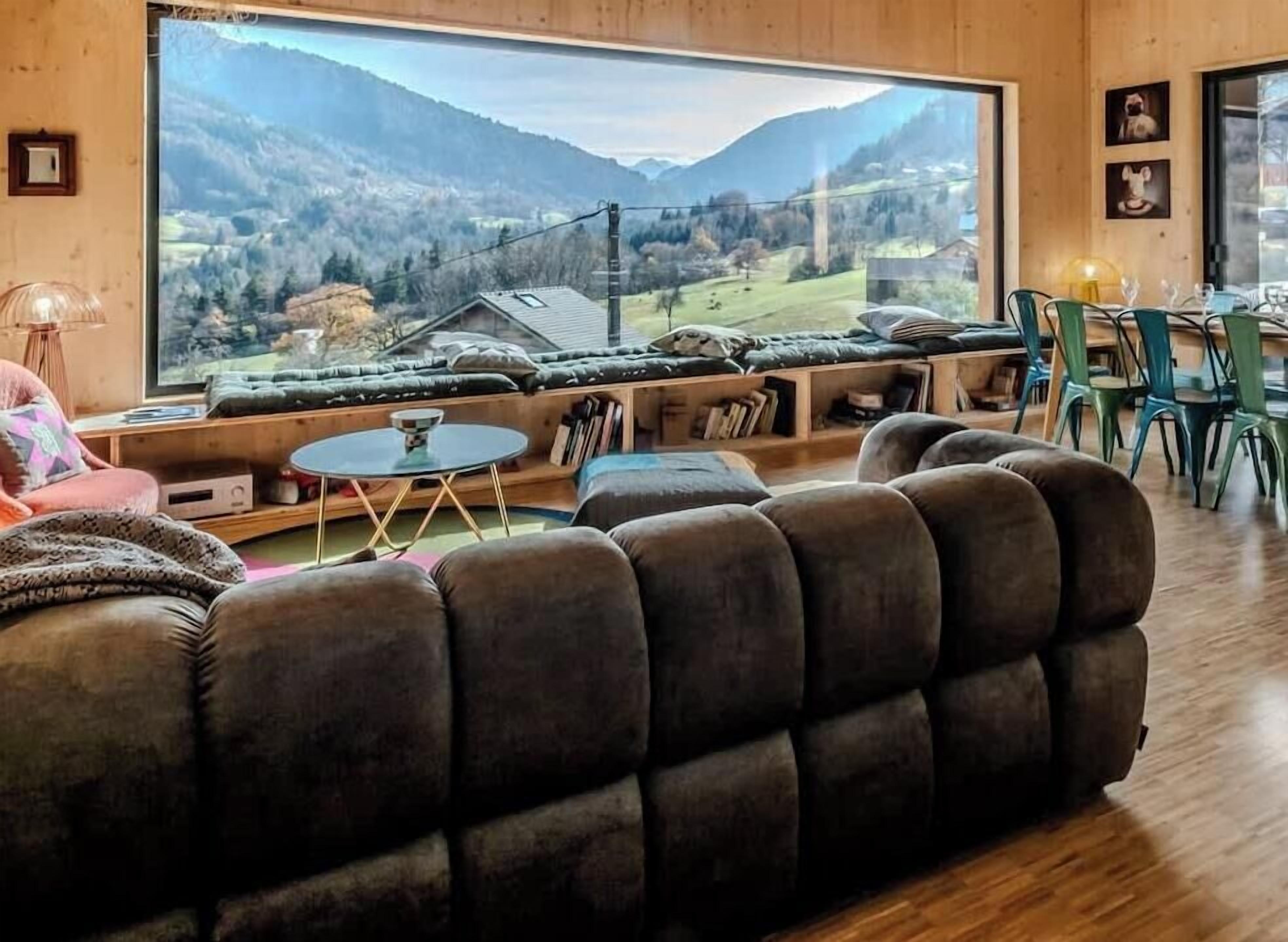 Un salon chaleureux avec une grande fenêtre donnant sur un paysage montagneux.