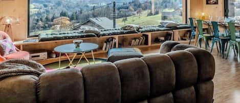 Un salon chaleureux avec une grande fenêtre donnant sur un paysage montagneux.