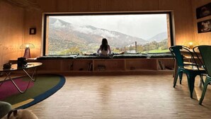 Ein gemütliches Zimmer mit einem großen Fenster, einer Holzbalkendecke und Blick auf Berge.