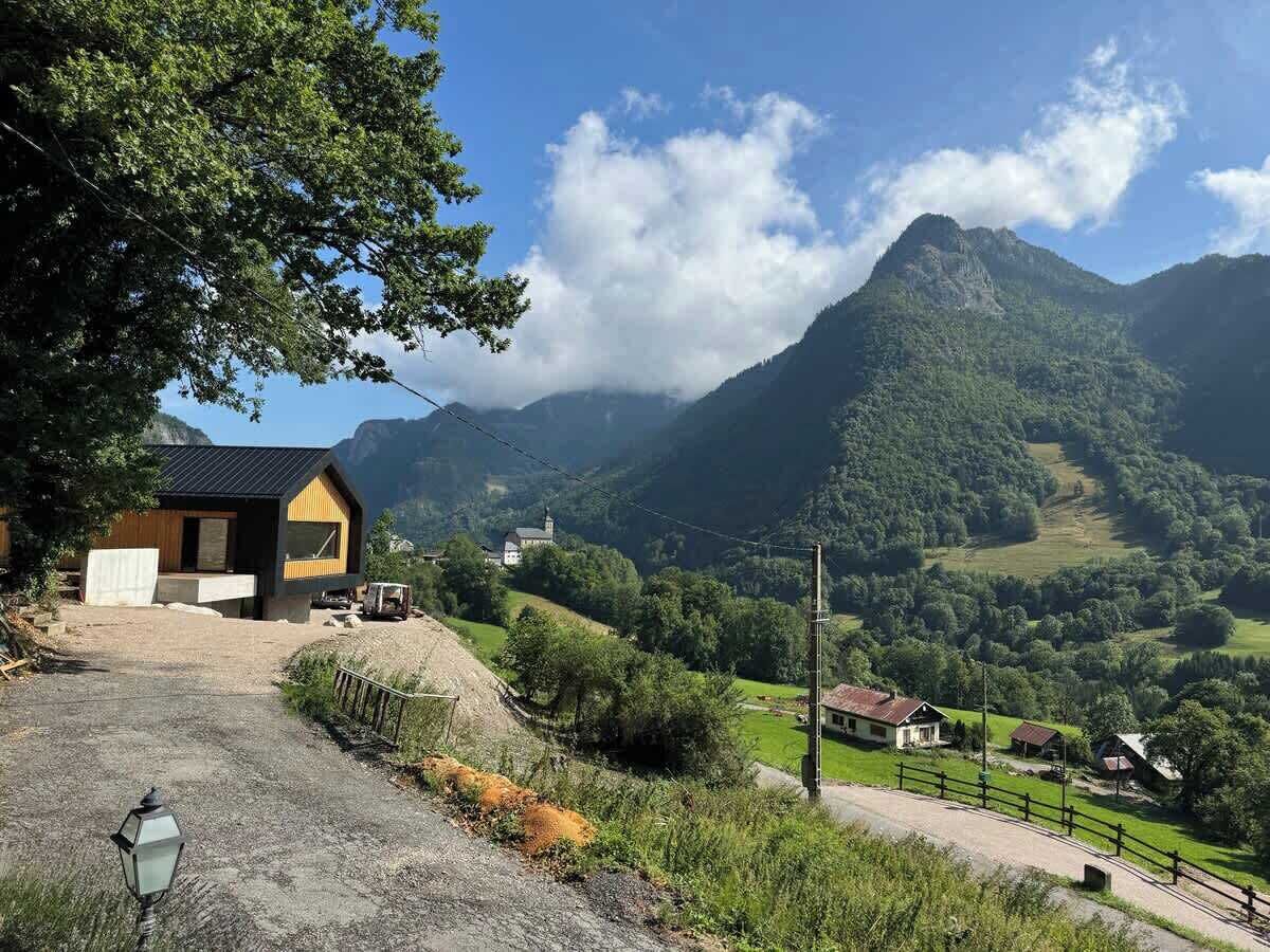 Een landelijk landschap met een huis, een berg en een heldere lucht.
