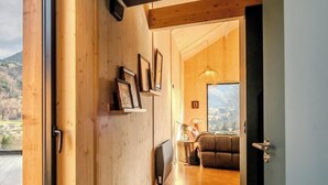 Ein modernes Interieur mit Holzwänden, ein Flur, der in einen Wohnbereich mit einer Couch und einem großen Fenster führt.