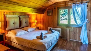 A wooden cabin bedroom with a bed, bedside lamps, and a window with curtains. - Le Chalet Brenor I Vue Lac I Lugrin (Lugrin)