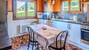 A cozy kitchen with wooden walls, a dining table with chairs, and a view of the outdoors. - Le Chalet Brenor I Vue Lac I Lugrin (Lugrin)