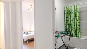 Una habitación de hotel con cama, baño con cortina de ducha de bambú y un tendedero.