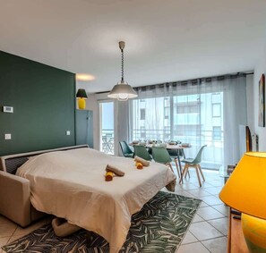 Ein Hotelzimmer mit Bett, Essbereich mit Stühlen, Tisch und Blick durch große Fenster.