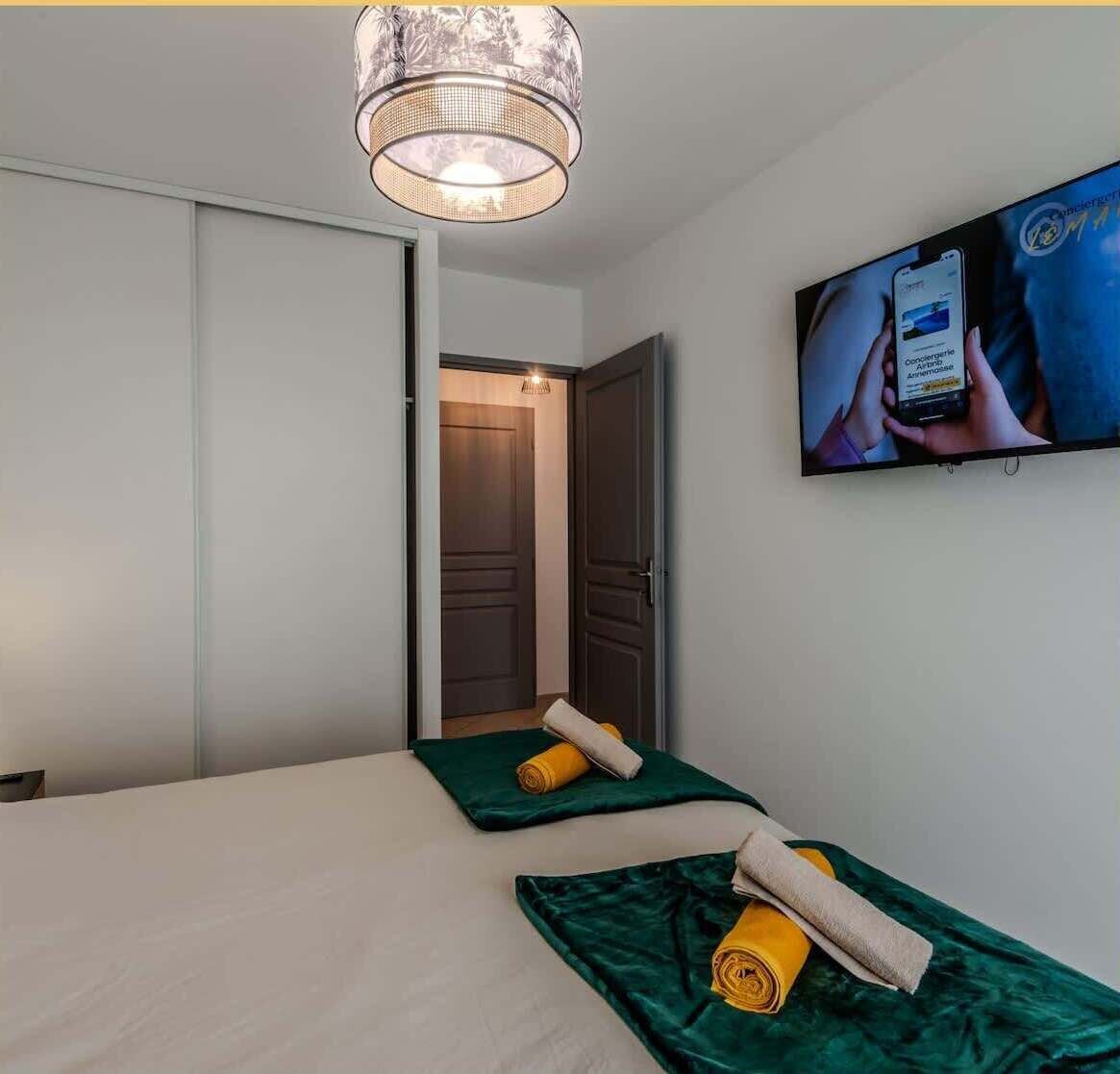 Ein Hotelzimmer mit einem Bett, einem an der Wand befestigten Fernseher und einer Tür zu einem weiteren Raum.