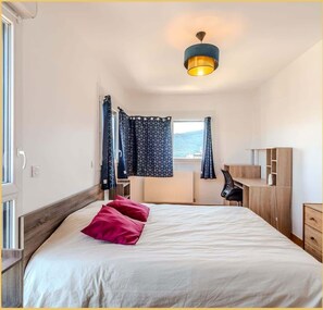 Ein Schlafzimmer mit einem Bett, einem Schreibtisch und einem Stuhl.