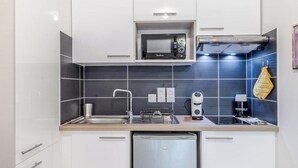 Una cocina moderna con armarios blancos, microondas, horno empotrado, pileta y lavavajillas.