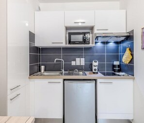 Eine moderne Küche mit weißen Schränken, einer Mikrowelle, einem Backofen, einer Spüle und einem Geschirrspüler.