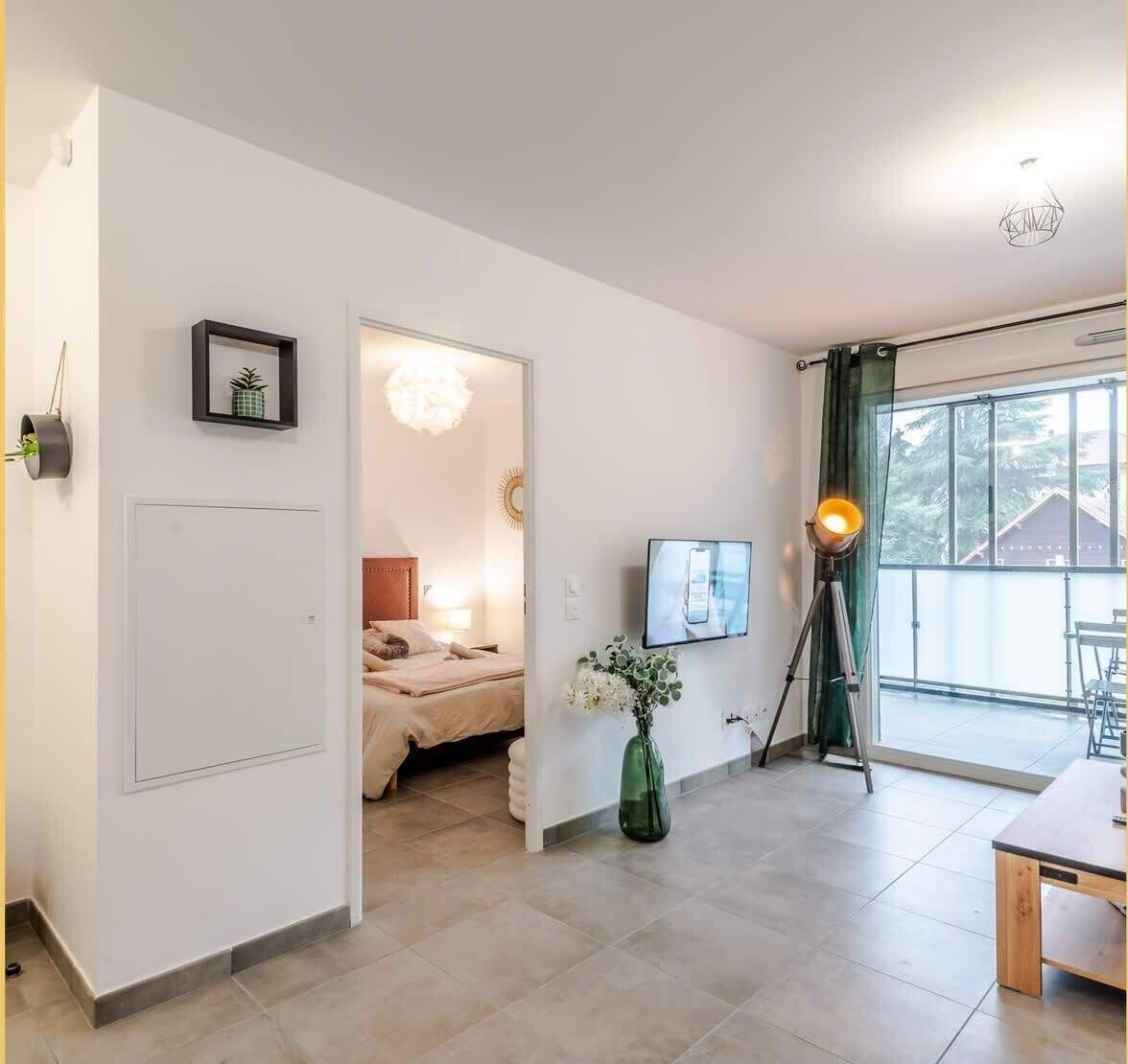 A modern hotel room with a bed, a desk, a TV, and a balcony with a view.