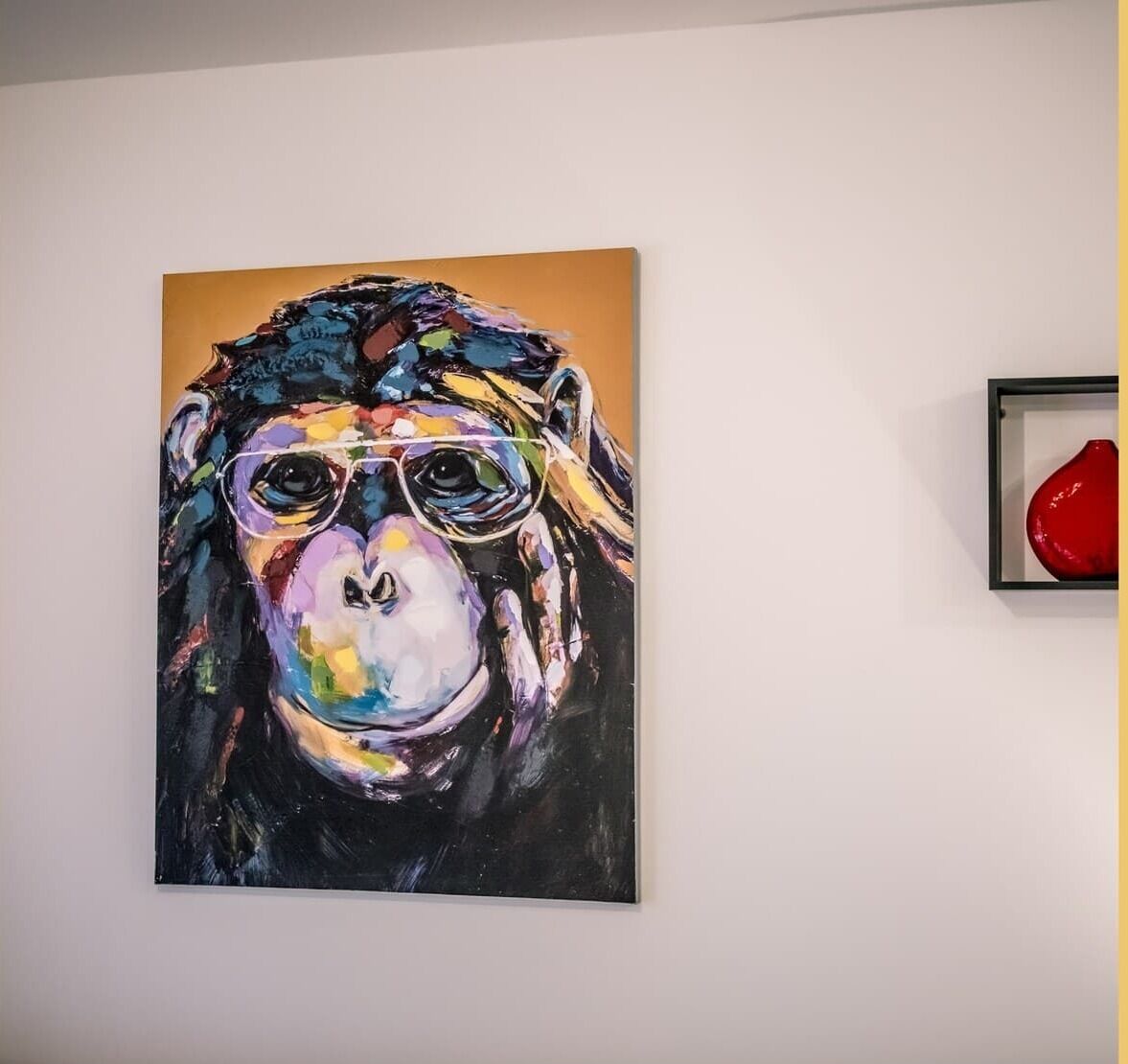 A painting of a monkey wearing glasses on a wall.