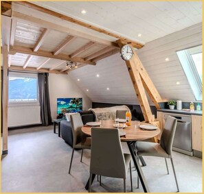Een eetruimte met een ronde tafel, stoelen en een klok aan de muur.