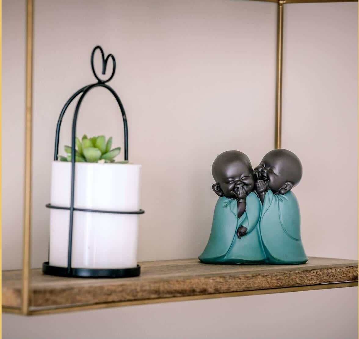 Une étagère avec un pot de fleurs blanc et deux statuettes.