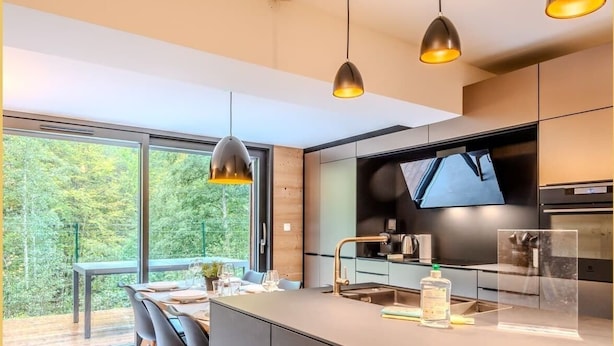 Una cucina moderna con una grande isola, illuminazione a sospensione e vista sull'esterno.