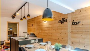 Una cucina moderna con pareti in legno, un'area pranzo per quattro persone e un cartello di un bar con caffè ben visibile.
