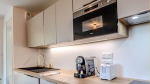 Une cuisine moderne équipée d’un four encastré, d’une machine à café et d’un grille-pain posés sur le plan de travail.