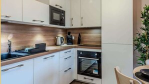 Une cuisine moderne avec des meubles blancs, un four à micro-ondes, un four traditionnel et une machine à café.