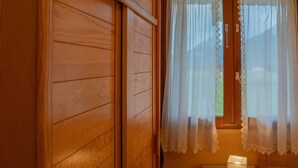 Una stanza in legno con un letto, un comodino e una finestra con tende leggere.