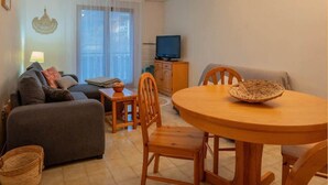Un accogliente soggiorno con un divano, un tavolo da pranzo con sedie, una televisione e una finestra con tende.