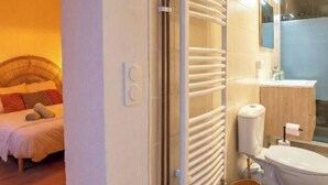 Una habitación de hotel con cama, radiador, inodoro y lavamanos.
