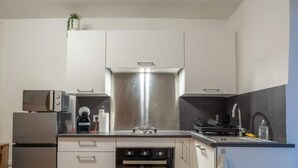Una cocina moderna con un refrigerador de acero inoxidable, un horno empotrado, un microondas y un lavamanos.