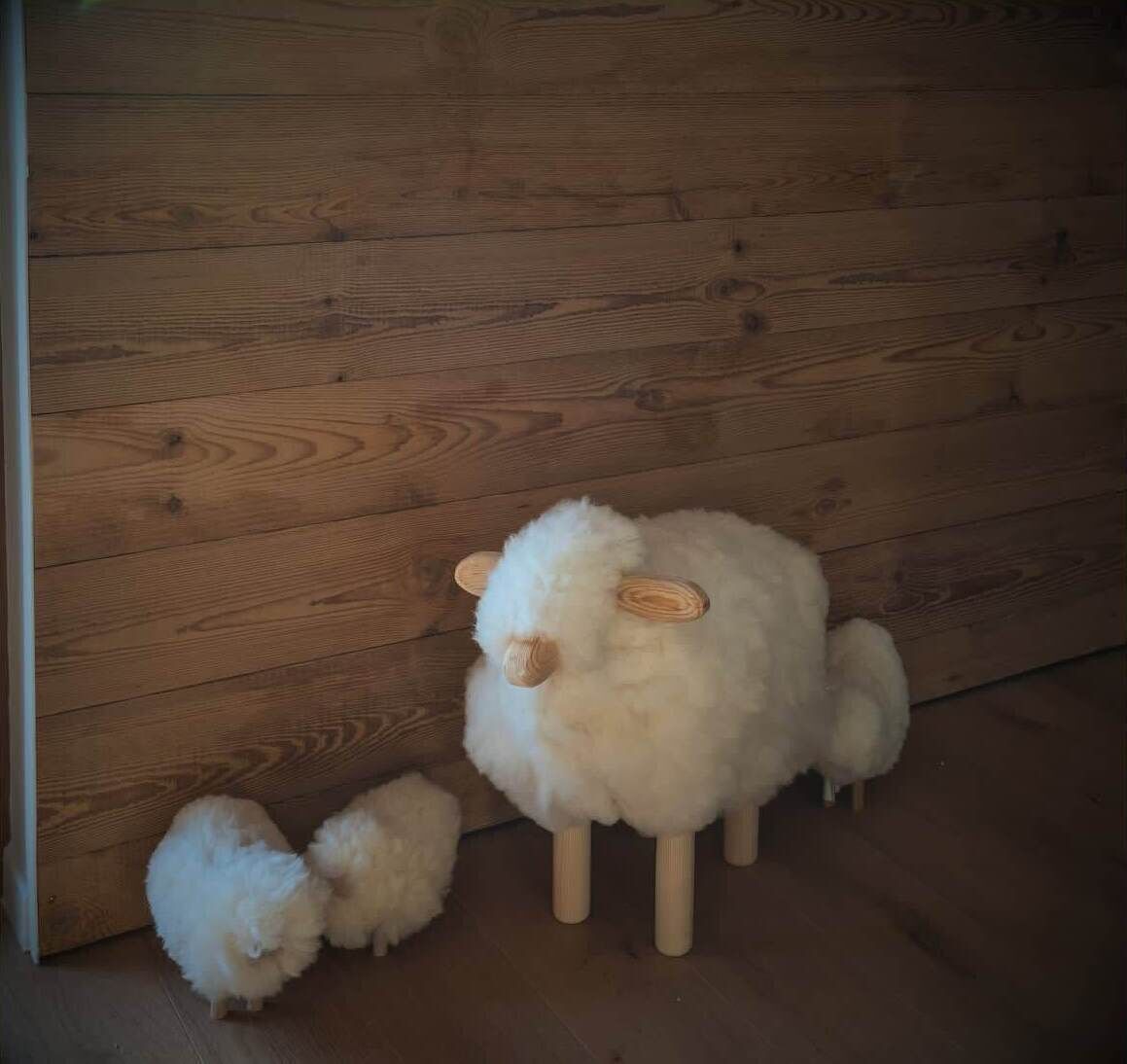 A room with wooden walls and a fluffy white object resembling a sheep on a stand.