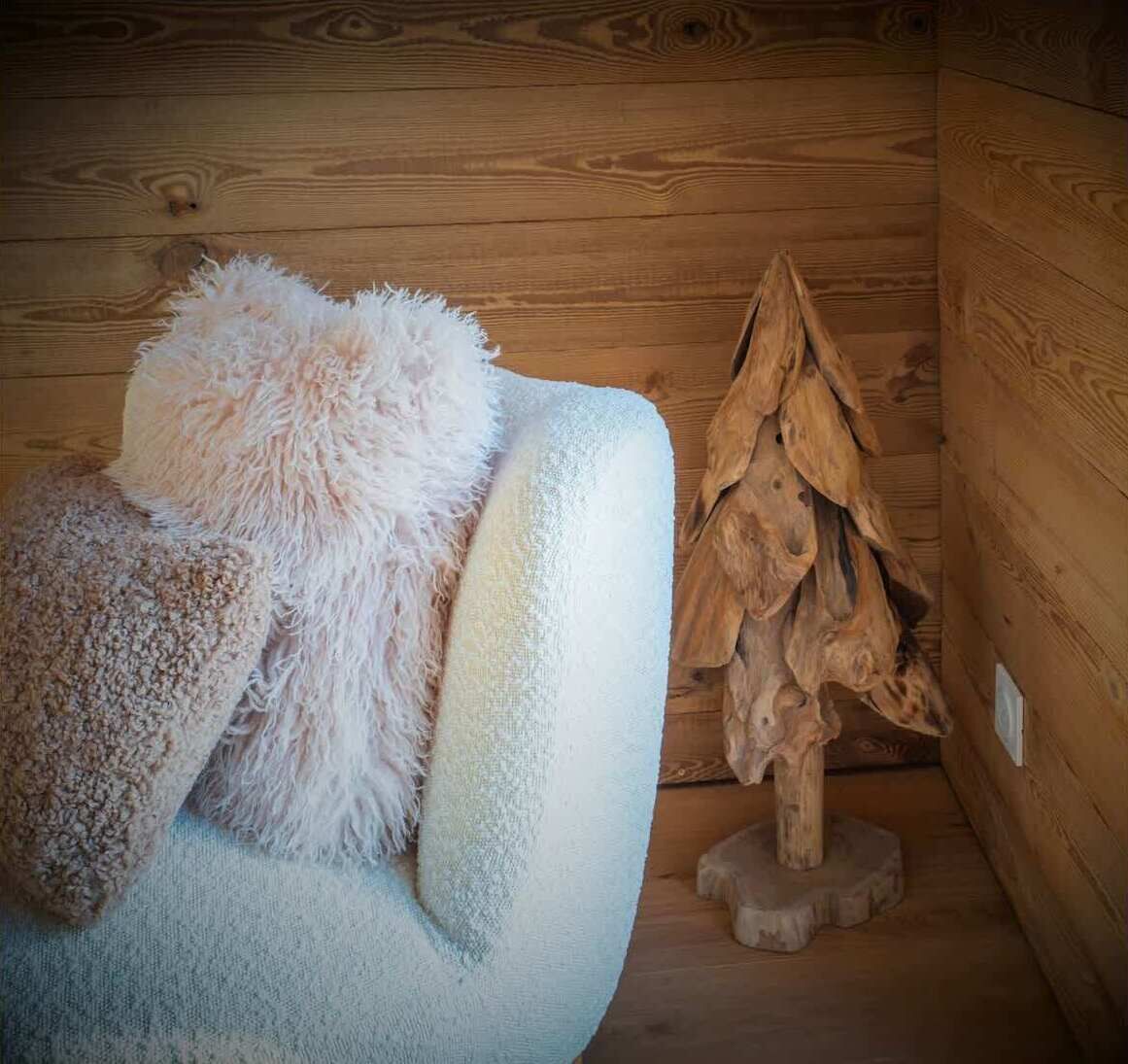 Ein gemütliches Zimmer mit einem bequemen Sessel, einer weichen Decke und einer einzigartigen Holzskulptur.