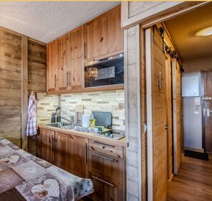 A compact kitchen with wooden cabinets, a built-in oven, and a tiled backsplash. - L'Alpenlake I Studio I Châtel (Châtel)