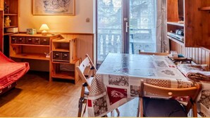 Un comedor acogedor con una mesa de madera, sillas y vistas a través de una puerta de cristal.