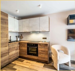 Eine moderne Küche mit Holzausstattung, einem eingebauten Ofen und einer Arbeitsplatte mit Wasserkocher.