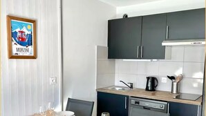 Een moderne keuken met donkere kastjes, een houten aanrecht en een eettafel gedekt voor vier personen.