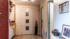 A hallway with a wooden door, a white door with three glass panels, a radiator, and a framed picture on a counter. - L'Etable de Larringes (Larringes)