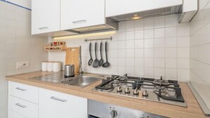 A modern kitchen with white cabinets, a stainless steel sink, and a gas stove. - Villa Marea, Praiano (Praiano)