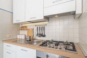 Eine moderne Küche mit weißen Schränken, einer Spüle aus Edelstahl und einem Gasherd.